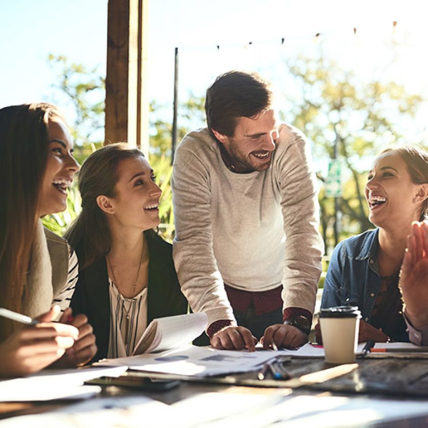 Groupe de personnes assistant à un atelier présentiel et échangeant autour d’une table dans une ambiance conviviale et détendue